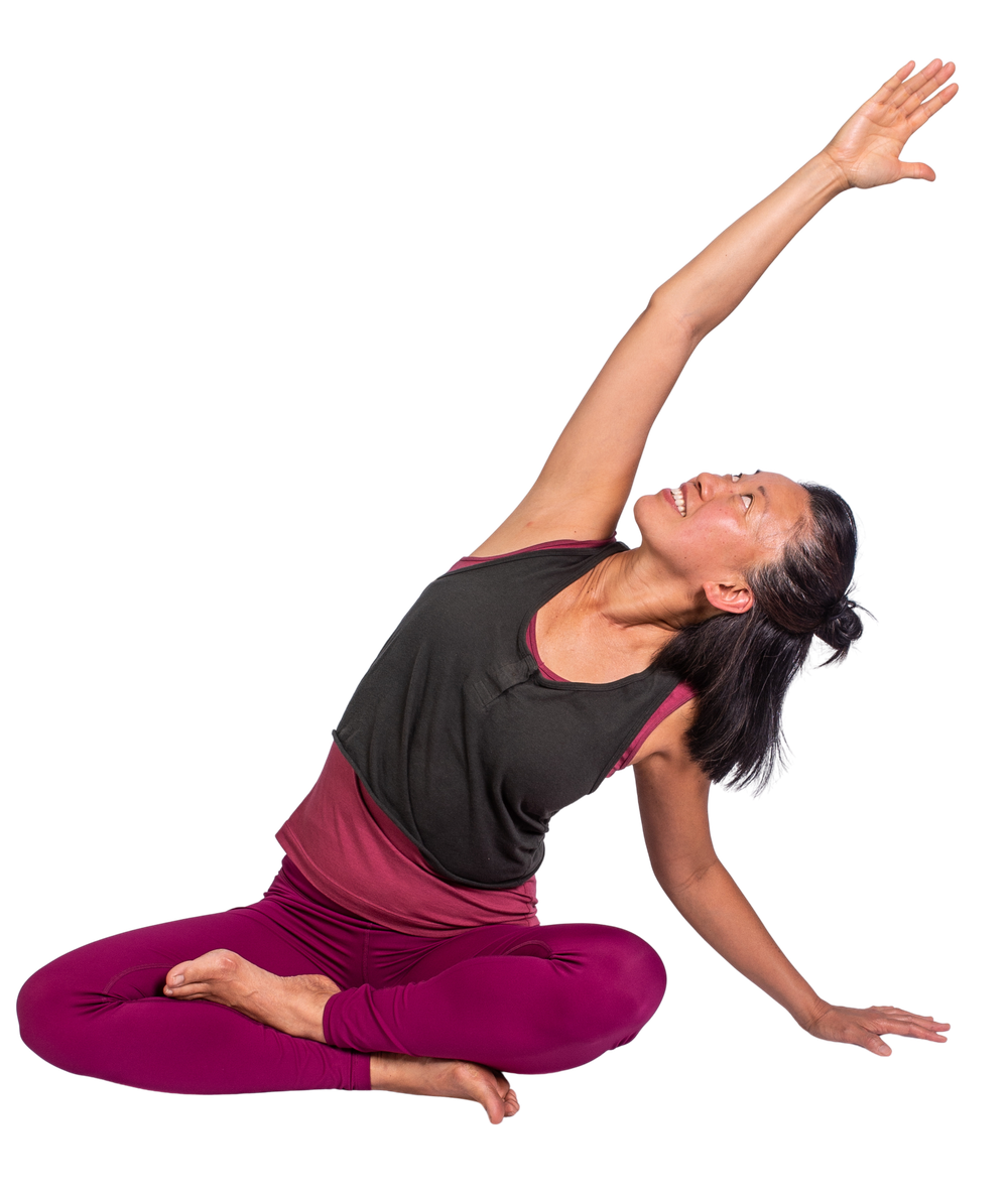 Eve Shen smiling mid-pose, reaching one arm overhead in a seated twist