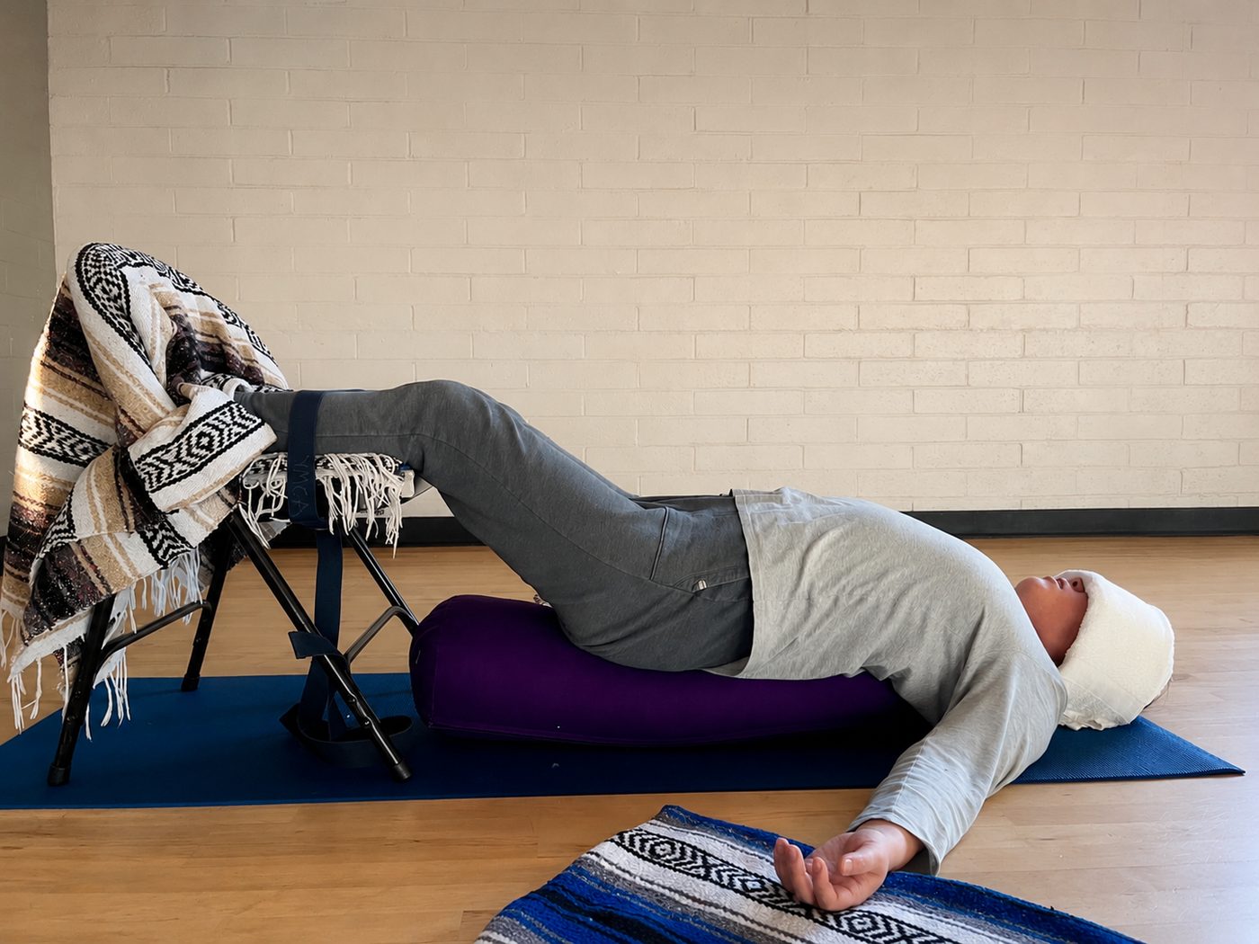 Supported restorative yoga pose using a chair, bolster, and blanket